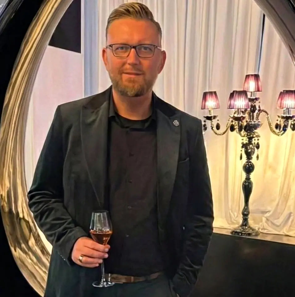 Sascha Frenz bei einer Abendveranstaltung mit einem Glas Wein.
